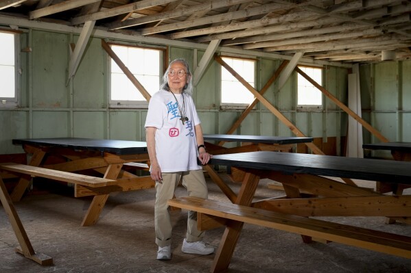 Sally Nakai Kobayashi, who was born at Minidoka in April of 1945, poses for a portrait in an original mess hall building similar to one her mother worked in at Minidoka National Historic Site, Saturday, July 8, 2023, in Jerome, Idaho. Kobayashi was visiting the site with her younger sister and son for the first time since 1945, when the camp closed following the end of World War II. (AP Photo/Lindsey Wasson)
