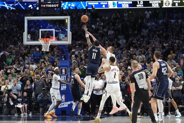 Dallas Mavericks guard Kyrie Irving (11) shoots the winning final-second basket against Denver Nuggets center Nikola Jokic, top center right, defends in an NBA basketball game in Dallas, Sunday, March 17, 2024. (AP Photo/LM Otero)