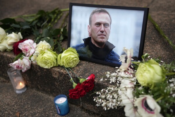 A portrait of Russian opposition leader Alexei Navalny and flowers are pictured as people gather near to Russian embassy to France, Friday, Feb. 16, 2024 in Paris. Alexei Navalny, Russia's top opposition leader and President Vladimir Putin's fiercest foe, died in prison on Friday, a statement from the Federal Penitentiary Service said. (AP Photo/Christophe Ena)