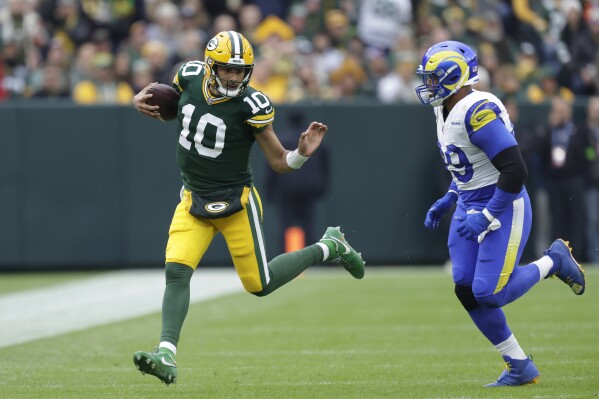 Green Bay Packers quarterback Jordan Love (10) runs with the football as Los Angeles Rams defensive tackle Aaron Donald (99) follows during the first half of an NFL football game Sunday, Nov. 5, 2023, in Green Bay, Wis. (AP Photo/Matt Ludtke)