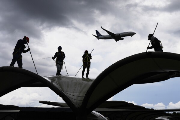 Workers clean a roof at the Tocumen International Airport in Panama City, Thursday, May 22, 2025, as Panama and Venezuela prepare to resume commercial flights nearly a year after suspending them when Panamanian President Jose Raul Mulino refused to recognize the re-election of Venezuelan President Nicolas Maduro. (AP Photo/Matias Delacroix)
