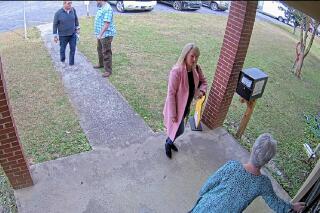 CORRECTS DATE TO JAN. 7, 2021. NOT JAN. 19 In this Jan. 7, 2021 image taken from Coffee County, Ga., security video, Cathy Latham, bottom, who was the chair of the Coffee County Republican Party at the time, greets a team of computer experts from data solutions company SullivanStrickler at the county elections office in Douglas, Ga. Records show that the team traveled to the rural south Georgia county to copy software and data from elections equipment. The Georgia secretary of state's office has said the visit was an "alleged unauthorized access" of election equipment. (Coffee County via AP)