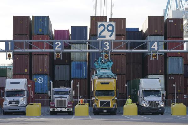 FILE - Trucks line up to have containers loaded from a stack at the Norfolk International Terminal Wednesday Dec 1, 2021, in Norfolk, Va.  Walmart workers who once unloaded trucks now have a chance to drive them. The nation’s largest retailer has launched a training program for employees who work in its distribution or fulfillment centers.   (AP Photo/Steve Helber, File)