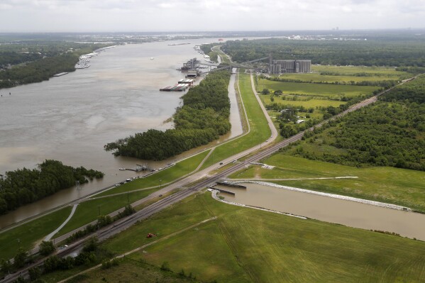 FILE - This May 1, 2019, file photo, shows the Davis Pond Diversion, a project that diverts water from the Mississippi River, left, into the Barataria Basin to reduce coastal erosion in St. Charles Parish, La. Officials are breaking ground in southeast Louisiana on a nearly $3 billion project to fight coastal wetland loss. It involves building massive gates in a section of levee in a rural area southeast of New Orleans and creating a channel to divert some of the Mississippi River’s sediment-laden water into an area known as the Barataria Basin. (AP Photo/Gerald Herbert, File)