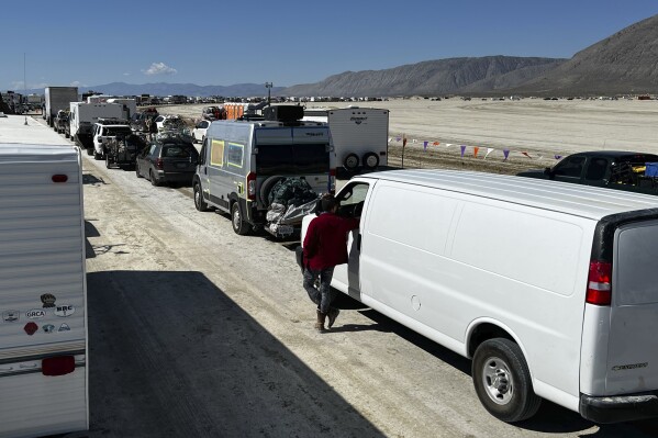 Vehicles line up to leave the Burning Man festival in Black Rock Desert, Nev., Tuesday, Sept. 5, 2023. The traffic jam leaving the festival eased up considerably Tuesday as the exodus from the mud-caked Nevada desert entered a second day following massive rain that left tens of thousands of partygoers stranded there for days.(Monique Sady via AP)