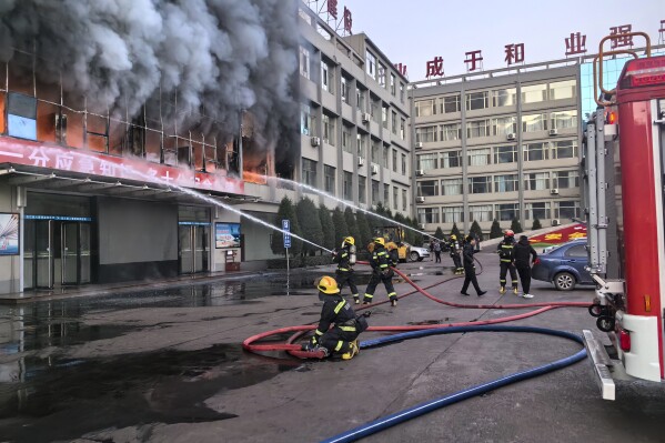 In this photo released by Xinhua News Agency, firefighters try to put out a fire at a building of the the Yongju Coal Company in Lyuliang city in northern China's Shanxi province, on Thursday, Nov. 16, 2023. A fire in the coal company building in a northern Chinese city has killed dozens of people and injured others. (Xinhua via AP)