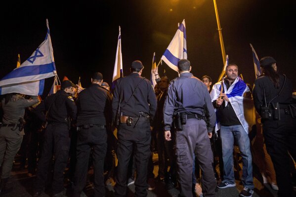 
              Israeli protesters hold flags during a demonstration against the cease-fire between Israel and Gaza's Hamas in the southern Israeli city of Ashkelon, Wednesday, Nov. 14, 2018. Israel's defense minister on Wednesday abruptly resigned to protest a new cease-fire with Hamas militants in Gaza, throwing the government into turmoil and pushing the country toward an early election. (AP Photo/Tsafrir Abayov)
            