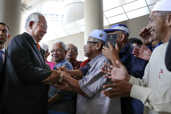 Former Malaysian Prime Minister Najib Razak, left, greets supporters as he arrives at Kuala Lumpur High Court in Kuala Lumpur, Malaysia, Monday, Nov. 11, 2019. An important court ruling Monday in the first corruption trial of Najib will be a test of the legal system and of the credibility of the prime minister who brought about his shocking ouster from office last year. (AP Photo/Vincent Thian)