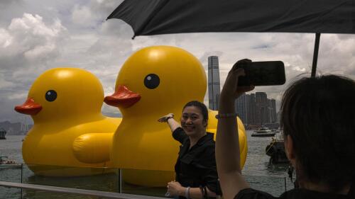 Members of the public photograph an art installation called "Double Ducks" by Dutch artist Florentijn Hofman at Victoria Harbour in Hong Kong, Friday, June 9, 2023. Two giant inflatable ducks made a splash in Hong Kong's Victoria Harbor on Friday, marking the return of a pop-art project that sparked a frenzy in the city a decade ago. (AP Photo/Louise Delmotte)