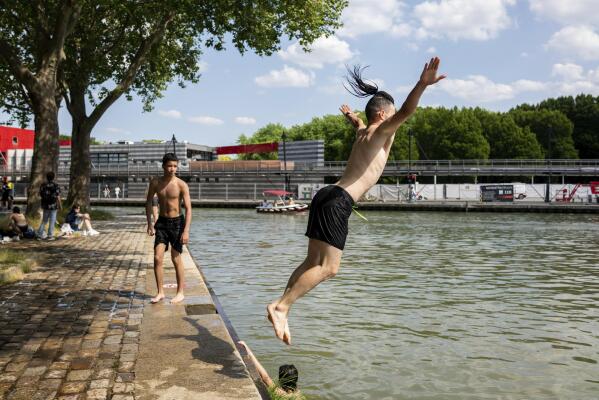 Youths dive in the Canal de l'Ourcq Wednesday, June 16, 2021 in Paris. Temperatures rose up to 33 degrees Celsius (91 degrees Fahrenheit) in the French capital. (AP Photo/Benjamin Girette)