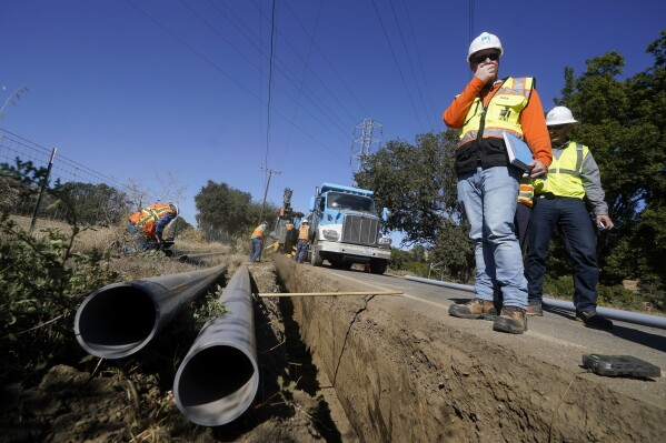 FILE - Paul Standen, senior director of underground regional delivery, second from right, and project manager Jeremy Schanaker, right, look on during a tour of a Pacific Gas and Electric crew burying power lines in Vacaville, Calif., Wednesday, Oct. 11, 2023. A California legislative committee will consider a bill that aims to crack down on investor-owned utilities spending money from ratepayers on advertising and political lobbying. (AP Photo/Jeff Chiu, File)