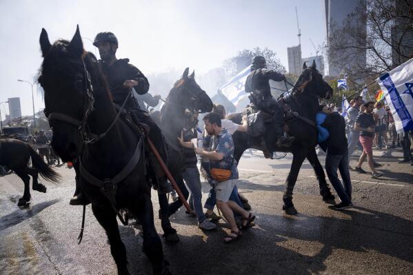 Israeli police deploy horses and stun grenades to disperse Israelis blocking a main road during a protest against plans by Prime Minister Benjamin Netanyahu's new government to overhaul the judicial system, in Tel Aviv, Israel, Wednesday, March 1, 2023. (AP Photo/Oded Balilty)