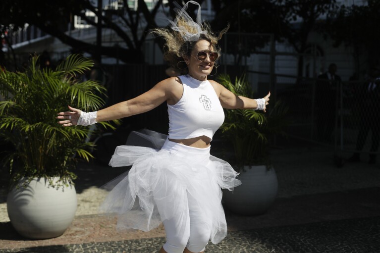 Ein Madonna-Fan tanzt vor dem Copacabana Palace Hotel, in dem Madonna übernachtet, vor ihrem Konzert in Rio de Janeiro, Brasilien, am Freitag, dem 3. Mai 2024. Madonna wird ihre Tour am Samstag mit einem kostenlosen Konzert am Strand der Copacabana abschließen.  (AP Photo/Bruna Prado