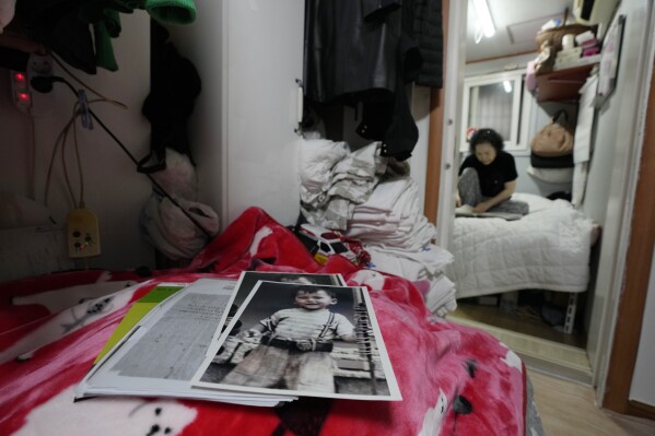 Photos of Choi Young-ja's son, Paik Sang-yeol, who went missing in 1975, sit on a bed in her motel room in Seoul, South Korea, Tuesday, March 5, 2024. (AP Photo/Ahn Young-joon, File)