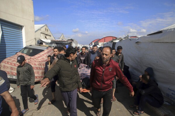 Palestinians carry a a body of a person killed in the Israeli bombardment at a building of an UNRWA vocational training center which displaced people use as a shelter in Khan Younis, southern Gaza Strip, Wednesday, Jan. 24, 2024. (AP Photo/Ramez Habboub)