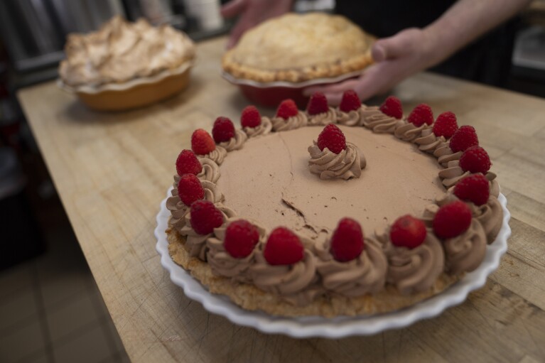 Manager Stephen Jarrett places pies on a counter at Michele's Pies, Wednesday, March 13, 2024, in Norwalk, Connecticut.  Math enthusiasts and bakers celebrate Pi Day on March 14 or 3/14, the first three digits of a mathematical constant with many practical uses.  Around the world, many people celebrate the day with a slice of sweet or savory pie.  (AP Photo/John Minchillo)