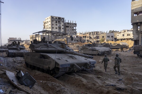 FILE - Israeli army troops are seen next to a destroyed building during a ground operation in the Gaza Strip on Nov. 8, 2023. As the military sets its sights on southern Gaza in its campaign to stamp out Hamas, key challenges loom. International patience for a protracted invasion has begun to wear thin. And with some 2 million displaced Gaza residents staying in crowded shelters in the south in dire conditions, a broad military offensive there could unleash a new humanitarian disaster during the cold, wet winter. (AP Photo/Ohad Zwigenberg, File)