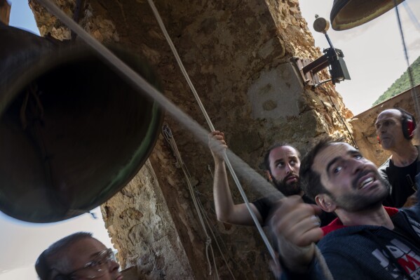 Students of the Vall d'en Bas School of Bell Ringers, perform playing all four bronze bells at the church bell tower of the12th-century Sant Romà church, at the tiny village of Joanetes, about two hours north of Barcelona, Spain, Saturday, June 29, 2024. A school set up to revive the manual ringing of church bells has graduated its first class of 18 students after learning their ringing skills. (AP Photo/Emilio Morenatti)