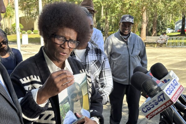 Mary Cure holds a framed photo of her slain son, Leonard Cure, as she speaks to reporters Wednesday, Oct. 18, 2023, in Woodbine, Ga. A Camden County sheriff's deputy fatally shot Leonard Cure after pulling him over for reckless driving on Oct. 16, 2023. Three years earlier, he was freed from a Florida prison after serving 16 years for an armed robbery that officials later concluded he didn't commit. (AP Photo/Russ Bynum)