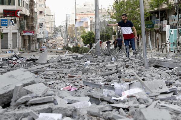 A man inspects the rubble of destroyed commercial building and Gaza health care clinic following an Israeli airstrike on the upper floors of a commercial building near the Health Ministry in Gaza City, on Monday, May 17, 2021. (AP Photo/Adel Hana)