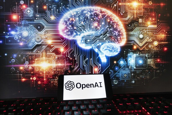 The OpenAI logo is displayed on a cell phone with an image on a computer monitor generated by ChatGPT's Dall-E text-to-image model, Friday, Dec. 8, 2023, in Boston. Europe's yearslong efforts to draw up AI guardrails have been bogged down by the recent emergence of generative AI systems like OpenAI's ChatGPT, which have dazzled the world with their ability to produce human-like work but raised fears about the risks they pose. (AP Photo/Michael Dwyer)