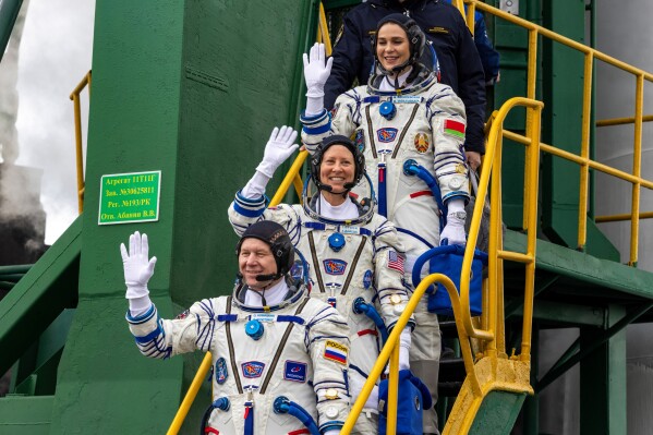 In this photo released by Roscosmos space corporation, NASA astronaut Tracy Dyson, centre, Oleg Novitsky of Roscosmos, bottom, and Marina Vasilevskaya of Belarus wave as they board to the space ship at the Russian leased Baikonur cosmodrome, Kazakhstan, Thursday, March 21, 2024. Russia's Roscosmos space agency has aborted the launch of three astronauts to the International Space Station about 20 seconds before they were scheduled to lift off. Officials say the crew is safe. The Russian Soyuz rocket was to carry NASA astronaut Tracy Dyson, Oleg Novitsky of Roscosmos and Marina Vasilevskaya of Belarus from the Russia-leased Baikonur launch facility in Kazakhstan. (Roscosmos space corporation via AP)