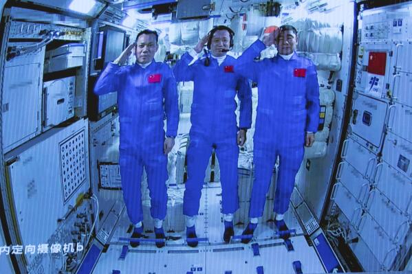 In this photo released by Xinhua News Agency, Chinese astronauts salute after successfully entering the Tianhe space station module as they are displayed on a big screen at the Beijing Aerospace Control Center in Beijing, on Thursday, June 17, 2021. China has launched the first three-man crew to its new space station in its the ambitious programs first crewed mission in five years (Jin Liwang/Xinhua via AP)