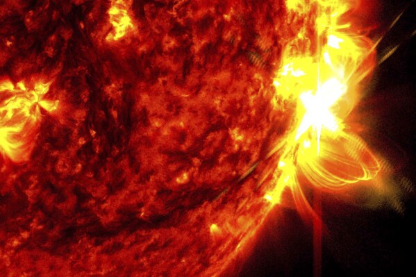 This image provided by NASA's Solar Dynamics Observatory shows a solar flare, right, on May 14, 2024, captured in the extreme ultraviolet light portion of the spectrum colorized in red and yellow. An international team of mathematicians and scientists reported Wednesday, May 22, 2024, that the sun's magnetic field originates much closer to the surface than previously thought. (NASA/SDO via AP)