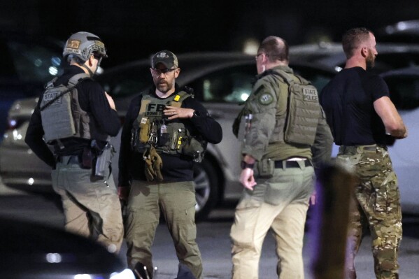 State police and an FBI bomb technician stand at a staging area in the parking lot of New Hampshire Hospital Friday, Nov. 17, 2023, in Concord, N.H. A fatal shooting at the New Hampshire psychiatric hospital Friday ended with the suspect dead, police said. New Hampshire Hospital is the state psychiatric hospital, located in the state’s capital city. (AP Photo/Michael Dwyer)