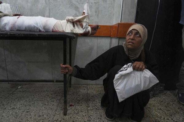 A Palestinian woman waits next to her son, who was injured last night while trying to get access to humanitarian aid, at the al-Shifa Hospital, in Gaza City, Wednesday, June 11, 2025. (AP Photo/Jehad Alshrafi)