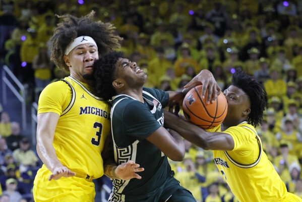 Michigan State guard Jase Richardson, center, is fouled by Michigan guard L.J. Cason, right, while also going to the basket against guard Tre Donaldson (3) during the first half of an NCAA college basketball game Friday, Feb. 21, 2025, in Ann Arbor, Mich. (AP Photo/Duane Burleson)