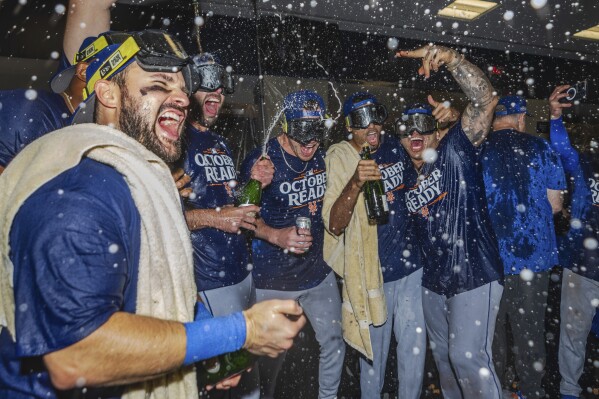 The New York Mets celebrate in the locker room after clinching a playoff berth with a victory in the first baseball game of a doubleheader against the Atlanta Braves, Monday, Sept. 30, 2024, in Atlanta. (AP Photo/Jason Allen)