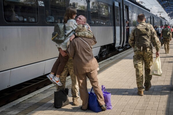 Un militar ucraniano abraza a su esposa y a su hija al despedirse de ellas para irse a combate en la estación de tren de Sloviansk, Ucrania, el 12 de septiembre de 2023. (Foto AP/Hanna Arhirova)