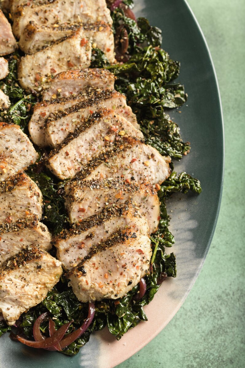 This image released by Milk Street shows a recipe for pork with kale, red wine and toasted garlic. (Milk Street via AP)