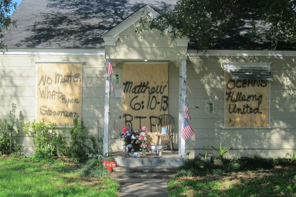 FILE - This Feb. 20, 2019, file photo shows a makeshift memorial with flowers and candles that has been set up at the front door of a home in Houston where a couple who lived there were killed during a Jan. 28, 2019, drug raid by Houston police. A second Houston police officer has been charged with murder and is among additional officers who have been indicted as part of an ongoing investigation into a Houston Police Department narcotics unit following the deadly 2019 drug raid, prosecutors announced Monday, Jan. 25, 2021. (AP Photo/Juan Lozano, File)
