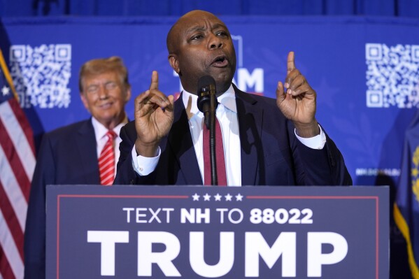 FILE - Republican presidential candidate former President Donald Trump, left, listens as Sen. Tim Scott, R-S.C., speaks at a campaign event in Concord, N.H., Jan. 19, 2024. Black voters support the reelection of President Joe Biden at a surprisingly low level, according to recent AP polling. For Republican strategists and former President Donald Trump, that's an opportunity to make inroads into the Democratic Party's most loyal voting bloc. Both parties are fine-tuning efforts to win over Black voters. Scott, who once challenged Trump for the GOP nomination, has emerged as one of his most prominent surrogates and speaks often about his record on race. (AP Photo/Matt Rourke, File)