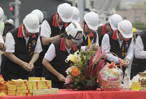 Huilien County magistrate Hsu Chen-wei, second from left, with government officials, offer prayers during the demolition ceremony for the partially collapsed building, two days after a powerful earthquake struck the city, in Hualien City, eastern Taiwan, Friday, April 5, 2024. (AP Photo/Chiang Ying-ying)