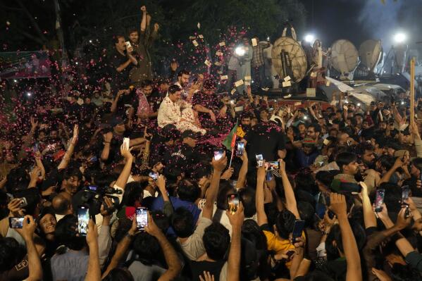 Supporters throw rose petals towards a vehicle carrying Pakistan's former Prime Minister Imran Khan to greet him upon his arrival at his home in Lahore, Pakistan, early Saturday, May 13, 2023. A high court in Islamabad on Friday granted Khan protection from arrest in a graft case and ordered him freed on bail. (AP Photo/K.M. Chaudary)