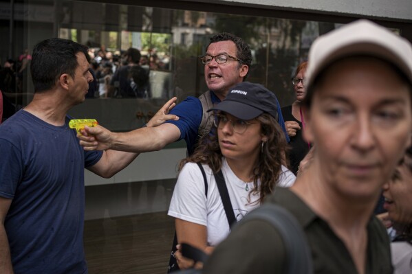 A protester holds a water gun during a protest against overtourism in Barcelona, Spain, Sunday, June 15, 2025. (AP Photo/Pau Venteo)