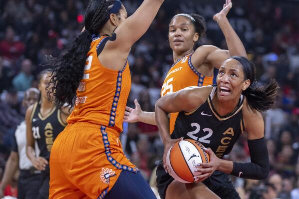 Las Vegas Aces forward A'ja Wilson (22) looks for a shot between Connecticut Sun center Brionna Jones (42) and forward Alyssa Thomas (25) during the first half in Game 1 of a WNBA basketball final playoff series Sunday, Sept. 11, 2022, in Las Vegas. (AP Photo/L.E. Baskow)