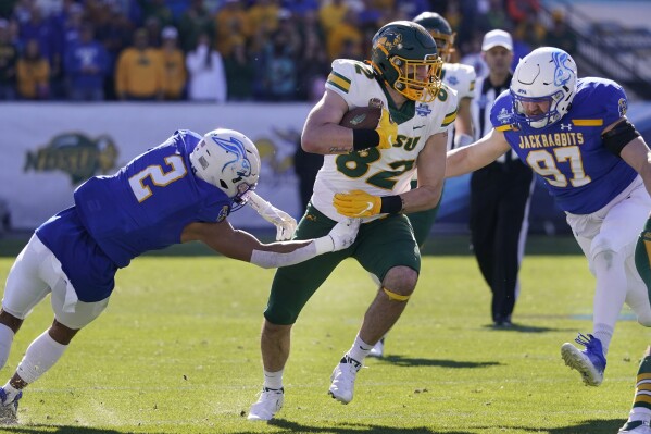 FILE - North Dakota State tight end Joe Stoffel (82) runs against South Dakota State's Isaiah Stalbird (2) and Reece Winkelman (97) during the FCS championship NCAA college football game Jan. 8, 2023, in Frisco, Texas. As the Football Championship Subdivision playoffs get started with eight games Saturday, defending champion and top-seeded South Dakota State will be among the eight teams enjoying a first-round bye. North Dakota State, the most dominant program over the past dozen years, finds itself in an unfamiliar spot in its 14th consecutive tournament - the first round. (AP Photo/LM Otero, File)