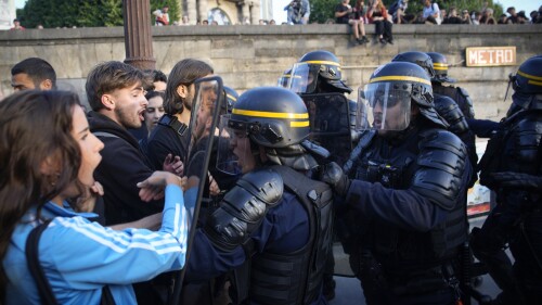 Police officers face protesters on Concorde square during a protest in Paris, France, Friday, June 30, 2023. French President Emmanuel Macron urged parents Friday to keep teenagers at home and proposed restrictions on social media to quell rioting spreading across France over the fatal police shooting of a 17-year-old driver. (AP Photo/Lewis Joly)