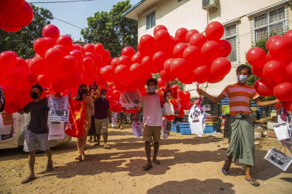 Anti-coup protesters hold red balloons attached with leaflets with various messages before they are released into the sky during a gathering Wednesday, March 24, 2021 in Yangon, Myanmar. Hundreds of people imprisoned for protesting last month's coup in Myanmar were released Wednesday in the first apparent gesture by the military to try to placate the protest movement. (AP Photo)