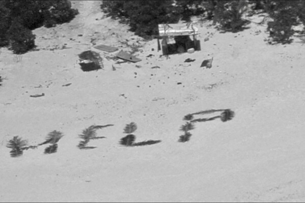 This photo provided by U.S. Coast Guard shows HELP" spelled out with palm fronds by three stranded mariners on Pikelot Atoll, Yap State, Federated States of Micronesia, Monday, April 8, 2024. The three mariners are safe after the coordination of U.S. Coast Guard Forces Micronesia/Sector Guam and the U.S. Navy, after being stranded for more than a week. (U.S. Coast Guard photo)