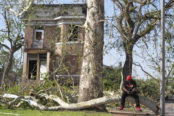 Steven Lampink sits on a downed tree after a severe storm moved through Friday, May 16, 2025, in St. Louis. (AP Photo/Jeff Roberson)