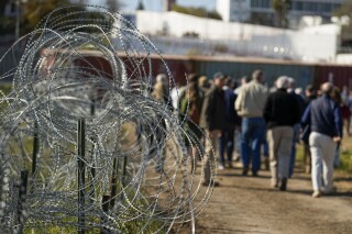 FILE - Concertina wire lines the path as members of Congress tour an area near the Texas-Mexico border, Jan. 3, 2024, in Eagle Pass, Texas. Social media users are misrepresenting a video from 2022 to make a convoy headed to the southern border look larger than it actually is. (AP Photo/Eric Gay, File)