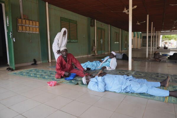 Worshippers rest following Friday prayers at a mosque in Niamey, Niger, Friday, July 28, 2023. The general who led a coup in Niger defended the takeover on state television and asked for support from the nation and international partners, as concerns grew that the political crisis could set back the country's fight against jihadists and increase Russia's influence in West Africa. (AP Photo/Sam Mednick)