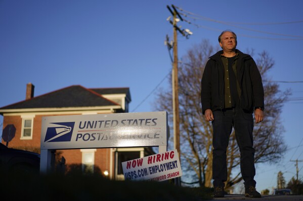 FILE - Gerald Groff, a former postal worker whose case will be argued before the Supreme Court, stands during a television interview near a "Now Hiring" sign posted at the roadside at the United State Postal Service, March 8, 2023, in Quarryville, Pa. The Supreme Court on Thursday, June 29, used the case of a Christian mailman who didn't want to work Sundays to solidify protections for workers who are religious. In a unanimous decision the justices made clear that workers who ask for religious accommodations, such as taking the Sabbath off, should get them unless their employers show doing so would result in “substantial increased costs” to the business. (AP Photo/Carolyn Kaster, File)