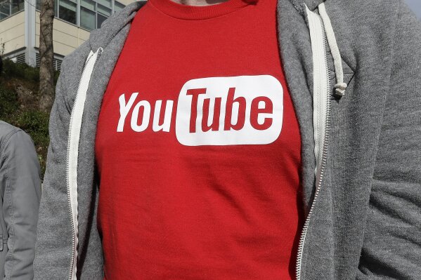 FILE - This April 4, 2018, file photo shows a YouTube logo on a t-shirt worn by a person near a YouTube office building in San Bruno, Calif. YouTube is taking another step to curb hateful and violent speech on its site. The video streaming company said it will now take down videos that lob insults at people based on race, gender expression or sexual orientation. (AP Photo/Jeff Chiu, File)