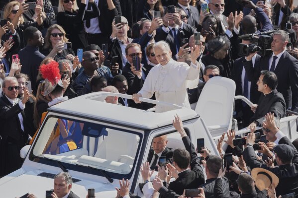 Pope Leo XIV waves from aboard the popemobile as he is driven through the crowd for the formal inauguration of his pontificate with a Mass in St. Peter's Square attended by heads of state, royalty and ordinary faithful, Sunday, May 18, 2025. (AP Photo/Stefano Costantino)